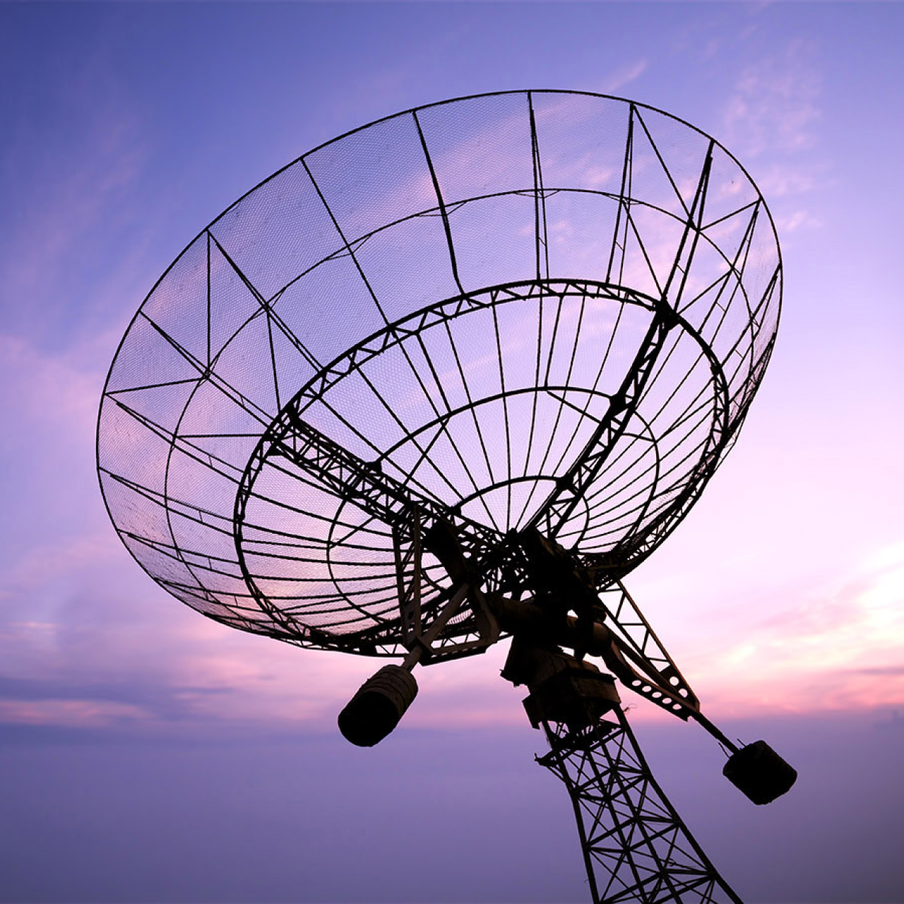 Fotografía de una antena parabólica en un atardecer.